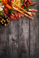 Antipasti, a traditional Italian snack on a dark wooden table. Sliced meat. Top view. Copy the space.