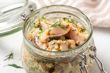 Pickled herring in a glass jar. Senapssill. Pickled herring with mustard, vinegar, onion, oil, dill, and sour cream. Scandinavian cuisine.