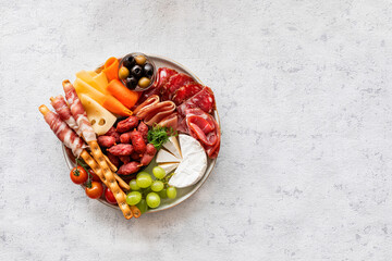 Antipasti, a traditional Italian snack on a light table. Sliced meat. Top view. Copy the space.