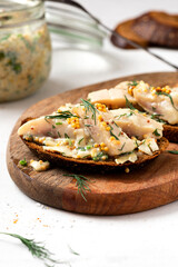 Sandwich with rye bread and pickled herring. Pickled herring with mustard, vinegar, onion, oil, dill, and sour cream. Scandinavian cuisine. Senapssill