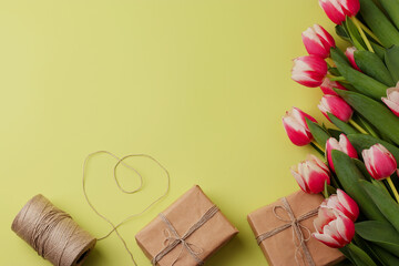 A festive bouquet of tulips, gift boxes in craft paper, natural material on a light background. Concept for Valentine's Day, Mother's Day, Women's Day, and Birthday. Flatlay, copy space.
