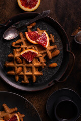 Belgian waffles with orange on a plate, flat lay