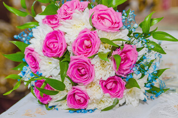 The bride's bouquet of roses and white chrysanthemums lies on a small table.