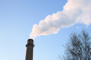 plant tubes with gray smoke on blue sky, chemical plant towers of nuclear power plant against the...