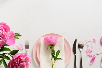 Spring romantic table setting with pink peony flowers on a white table. View from above. Space for text.