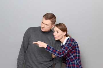 Surprised woman is holding man by arm and pointing to the side