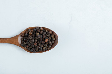 A wooden spoon full of dried pepper on a white background