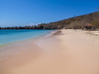 An areal, drone shot with a view on an idyllic Pink Beach on Lombok, Indonesia. Many boats drifting on a calm surface of the sea. Unspoiled, hidden gem. Perfect place for peaceful, relaxed holidays