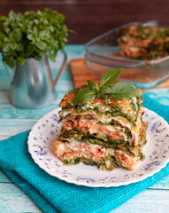 italian lasagna with salmon and spinach on a wooden background