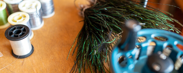 Fishing fly tying materials and tools on a wooden table