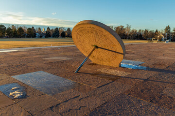 Beautiful sundial in the Cranmer Park, Denver, Colorado, with trees and Denver cityscape on...