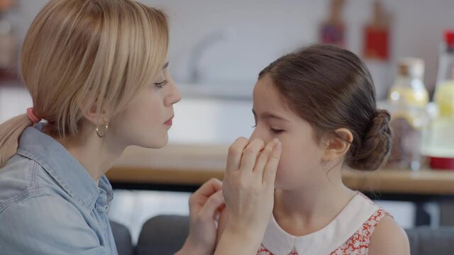 Young mother takes off the burr from her little daughter's eye. Mother daughter love.