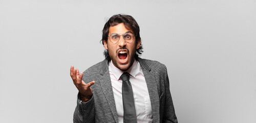 young handsome indian man looking angry, annoyed and frustrated screaming wtf or what’s wrong...