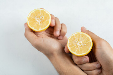 Hand holding a slice of lemon on a white background