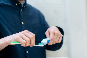 person squeeze toothpaste on a toothbrush in bathroom