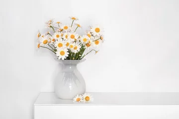 Foto op Canvas a bouquet of daisies in a white glass vase on a white table, flowers for grandmother's birthday, for women's day, flowers in a white interior © Leka