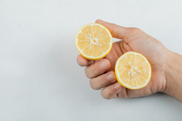 Hand holding a slice of lemon on a white background