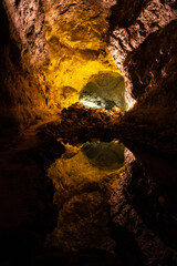 Cave lava tube illuminated with water reflection in Canary Islands. Geological cavern formation, tourist attraction concepts