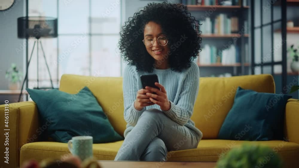 Poster portrait of a beautiful authentic latina female in a stylish cozy living room using smartphone at ho