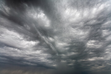 Dramatic gray clouds covered the entire sky before the rain. Low clouds in waves and layers across the sky. Black and white sky