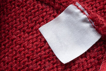 Blank laundry care clothes label on red knitted fabric texture background