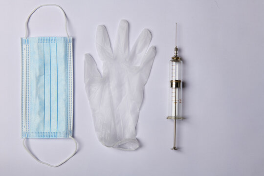 photo of a blue medical mask and gloves and a syringe