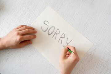 person hands holding a paper sheet with the sorry word
