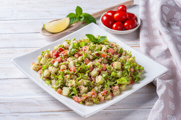 .Traditional Lebanese salad tabouli tabule with wheat, herbs, tomatoes, mint and lemon.