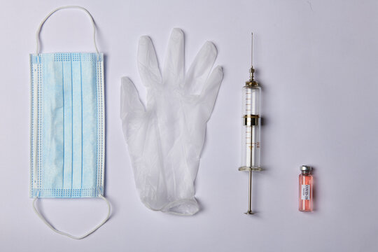 photo of blue medical mask and gloves and syringe and vaccine