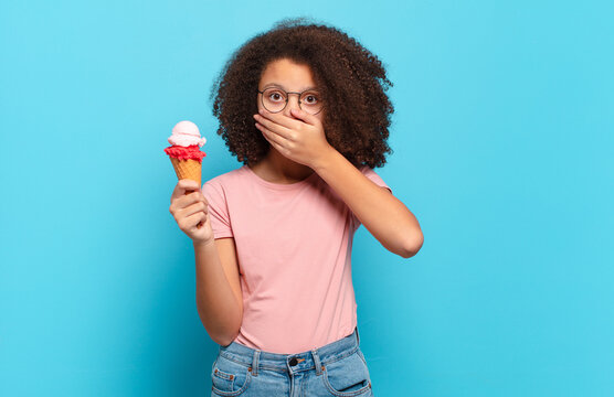 pretty afro teenager covering mouth with hands with a shocked, surprised expression, keeping a secret or saying oops. sumer ice cream concept