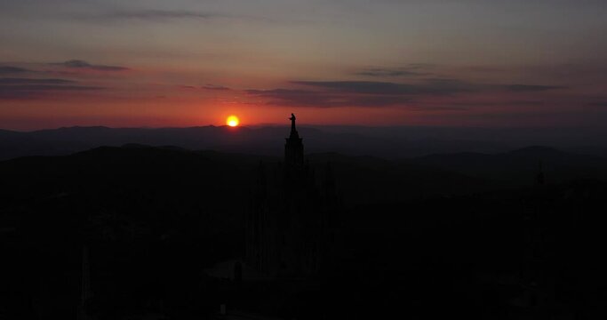 Aerial video front dolly movement of sunset in barcelona with tibidabo church in silhouette