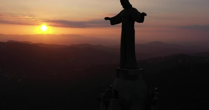 Aerial video with up pedestal movement of christ monument in Tibidabo with silluete in sunset