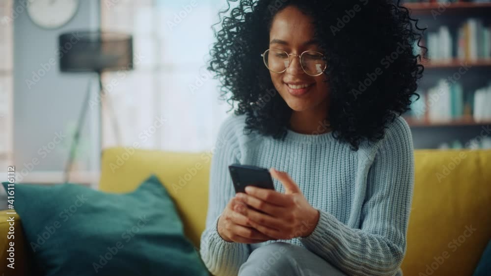 Poster portrait of a beautiful authentic latina female in a stylish cozy living room using smartphone at ho