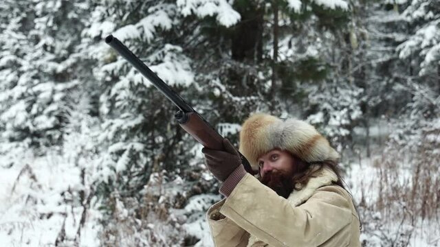 Male hunter in tradition clothers armed with rifle in snowy winter forest. High quality 4k footage