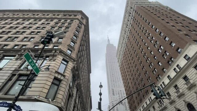 Herald Towers and Empire State Building 34th Street upward angle view snowing in winter storm Manhattan New York City NYC