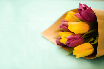 Greeting card for Women's Day on March 8. Bouquet of yellow-lilac tulips on a blue background. Close-up. Copy space for text.