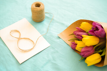 Greeting card for Women's Day on March 8. Bouquet of yellow-lilac tulips on a blue background. Close-up. Copy space for text.