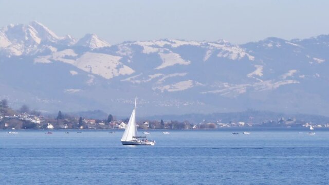 Static shot of a sailboat on the lake of Zurich, big mountains in Switzerland.