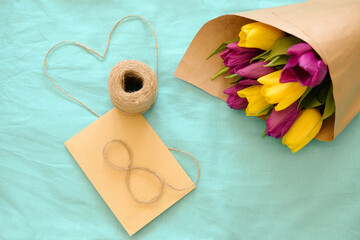 Greeting card for Women's Day on March 8. Bouquet of yellow-lilac tulips on a blue background. Close-up. Copy space for text.
