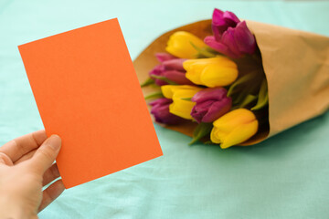 Greeting card for Women's Day on March 8. Bouquet of yellow-lilac tulips on a blue background. Close-up. Copy space for text.