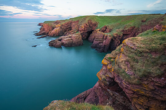 Coastal landscape of the red sandstone Seaton Cliffs during sunset or sunrise at Arbroath east coast of Angus, Scotland.
