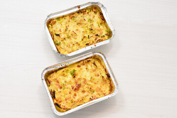 Baked chicken and mushroom cannelloni, bathed in cream in cheese sauce gratin on white wooden background