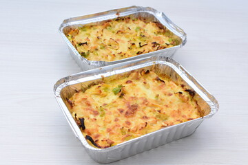 Baked chicken and mushroom cannelloni, bathed in cream in cheese sauce gratin on white wooden background