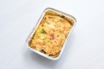 Baked chicken and mushroom cannelloni, bathed in cream in cheese sauce gratin on white wooden background