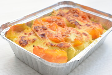 Baked chicken and mushroom cannelloni, bathed in cream in cheese sauce gratin on white wooden background
