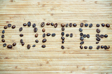 Ziarna kawy wysypane na drewniana deskę. Ziarna te tworzą napis COFFEE © Miosz