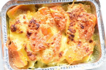 Baked chicken and mushroom cannelloni, bathed in cream in cheese sauce gratin on white wooden background