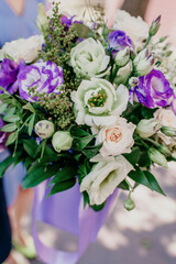 Beautiful large bouquet of pale and violet eustoma end white roses in hands of guy. Man holding beautiful garden flowers for gift. Close up, floral concept