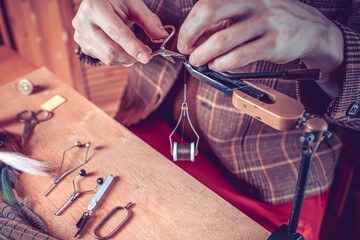 Close up on young man's hands tying a fly for fishing