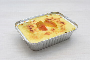 Baked chicken and mushroom cannelloni, bathed in cream in cheese sauce gratin on white wooden...